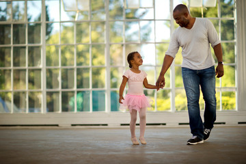 Smiling father holding hands with his young daughter.