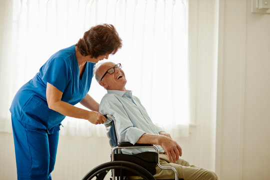 Female nurse comforting a senior man sitting in a wheelchair.