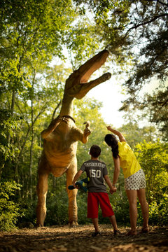 Mother and son looking up at an enormous statue of a dinosaur.