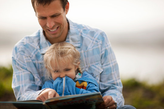 Smiling father enjoys reading a storybook to his little girl.