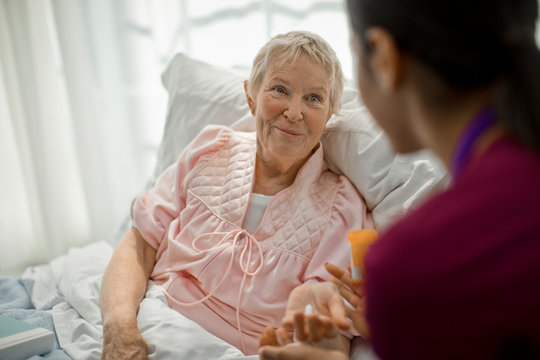 Senior woman receiving medication from nurse