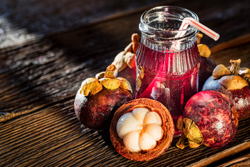 Fresh Mangosteen fruit and drink in jar on wooden background © Yakov