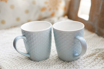 Two blue porcelain mugs standing on a knitted tablecloth