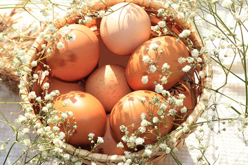 Natural Easter eggs in a basket on a table with wild spring flowers and grass, preparing for the Easter holiday