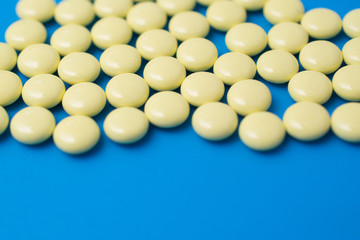 Yellow pills on blue background, painkiller or antibiotic concept