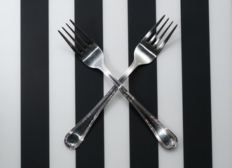 Forks. Crossed fork close-up on plate with striped background. 