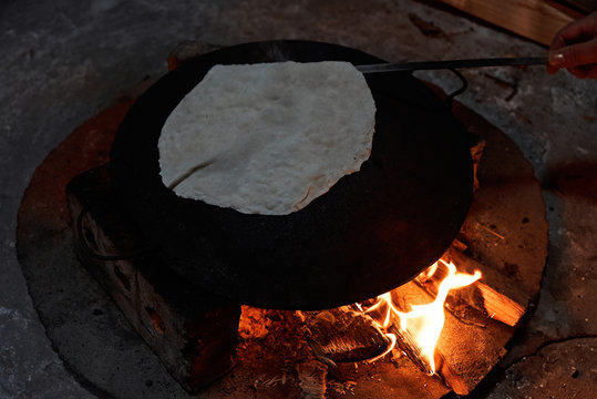 Pita bread baking on a saj or tava on fire, close-up