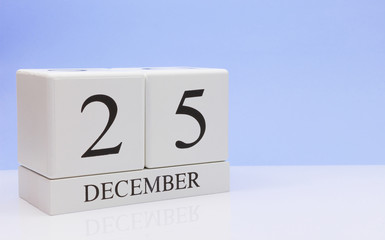 December 25st. Day 25 of month, daily calendar on white table with reflection, with light blue background. Winter time, empty space for text