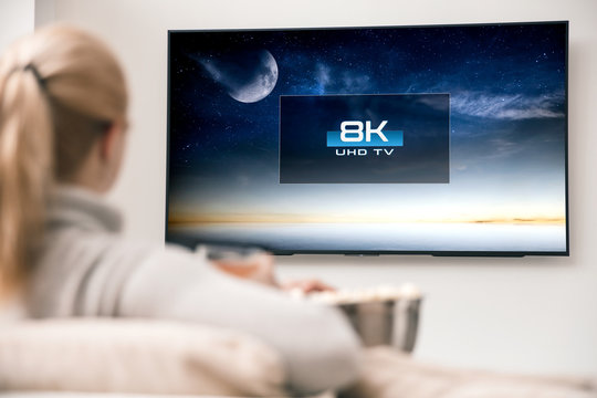 Woman watches tv with 8k ultra hd resolution. Picture on the screen created in graphic software.