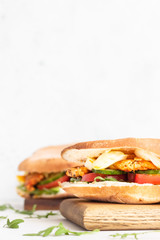 Pita with arugula, avocado, cucumber, tomatoes, chicken and egg. Sandwich with chicken, egg and vegetables. Light concrete background. Copy space.