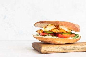 Pita with arugula, avocado, cucumber, tomatoes, chicken and egg. Sandwich with chicken, egg and vegetables. Light concrete background. Copy space.