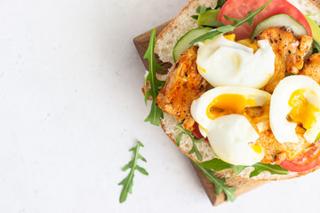 Pita with arugula, avocado, cucumber, tomatoes, chicken and egg. Sandwich with chicken, egg and vegetables. Light concrete background. Copy space.