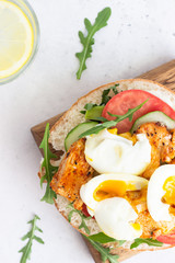 Pita with arugula, avocado, cucumber, tomatoes, chicken and egg. Sandwich with chicken, egg and vegetables. Light concrete background. Copy space.