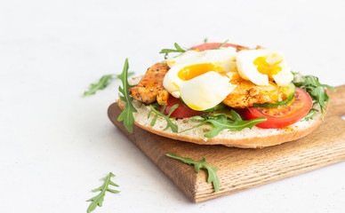 Pita with arugula, avocado, cucumber, tomatoes, chicken and egg. Sandwich with chicken, egg and vegetables. Light concrete background. Copy space.