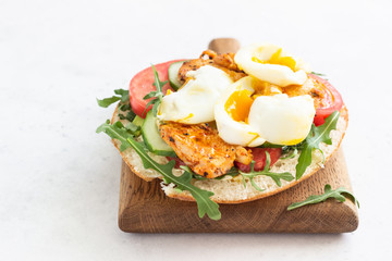 Pita with arugula, avocado, cucumber, tomatoes, chicken and egg. Sandwich with chicken, egg and vegetables. Light concrete background. Copy space.