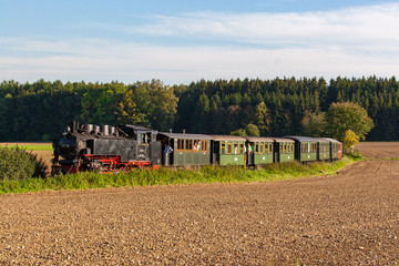 Schmalspur Dampflokomotive während der Fahrt in freier Landschaft