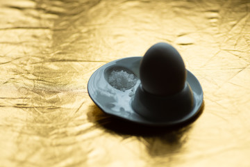 Fototapeta na wymiar boiled egg with spoon, stand and salt on gold