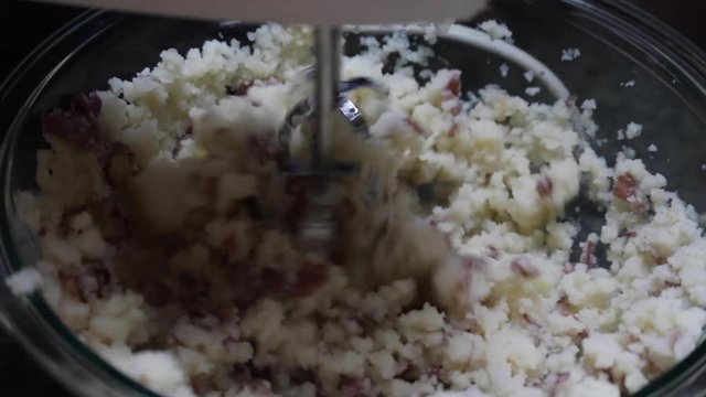 Close up, hand mixer blending potatoes