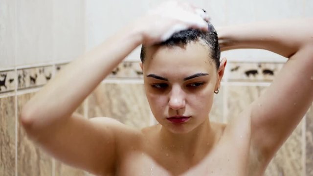 Beautiful naked woman washing long hair with shampoo