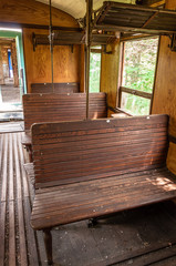 Blick in ein altes Zugabteil mit Holzsitzen und Ablagen und dem Mittelgang