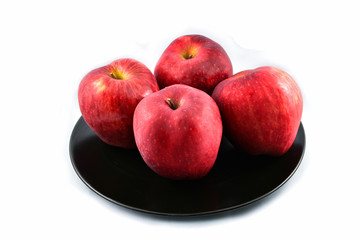 fresh red apple on black plate isolated on white background
