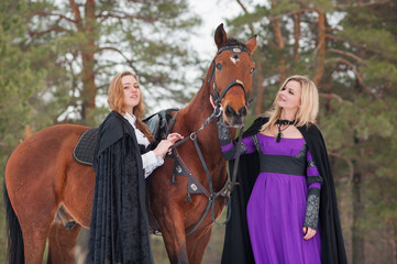 Two beautiful girls in historical clothes riding a horse