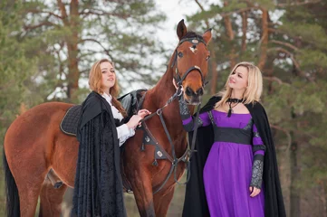 Foto op Canvas Two beautiful girls in historical clothes riding a horse © Rakursstudio