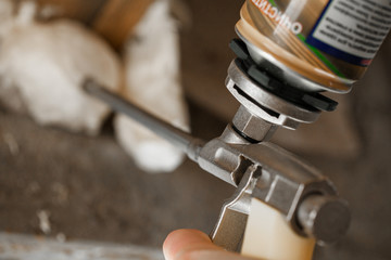Worker hand holding polyurethane expanding foam glue gun applicator. Construction foam sticking out...