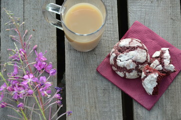 Red velvet cookies next to a cup of coffee. sunny spring or summer morning. pink purple flower