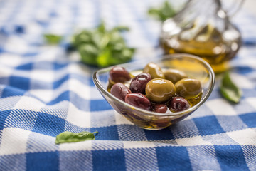 Green and red olives in bowl with olive oil and carafe in the background