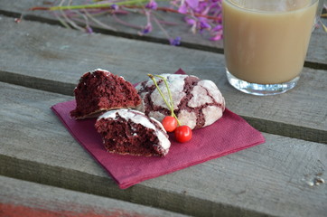 Red velvet cookies next to a cup of coffee. sunny spring or summer morning. pink purple flower