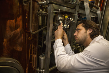 Professional engineer of modern factory checking and examining on quality machinery. Serious, concentrated man working with technologies and industrial equipment on brewery.