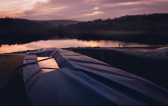 A beautiful pink and purple sunset behind a sailing boat under cover
