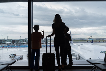 Silhouettes of mom with kids in terminal waiting for flight Travel Concept