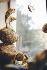 A cute Easter rabbit made of straw with a basket looking out the window