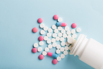 Assorted pharmaceutical medicine pills, tablets and capsules. Blue background.