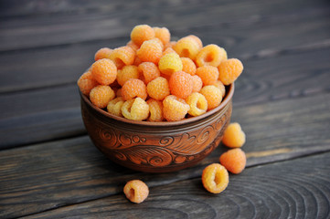yellow raspberries in a pottery on a wooden table. View from above