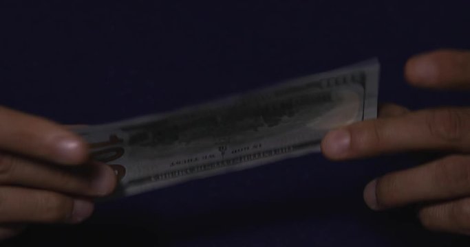 Hands showing a $100 bill to camera 