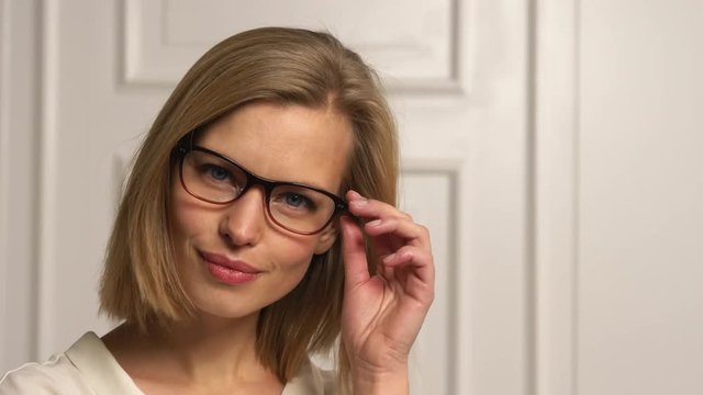 Beautiful blonde model with glasses winks on camera