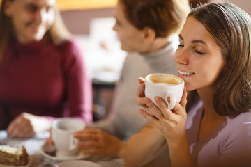 Girl, smiling and holding cup of hot coffee at bright cafe.