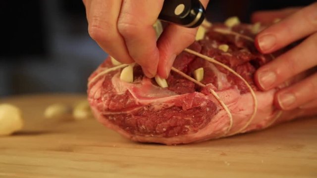 Low angle close up, putting garlic into raw beef tenderloin