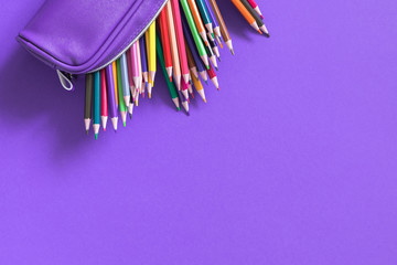 Color pencils in pencil-case on purple paper background. Back to school background. Flat lay, top view, copy space
