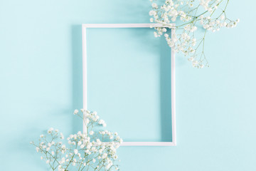 Flowers composition romantic. White gypsophila flowers, photo frame on pastel blue background....