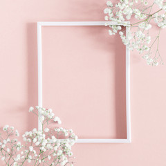 Flowers composition romantic. White gypsophila flowers, photo frame on pastel pink background....