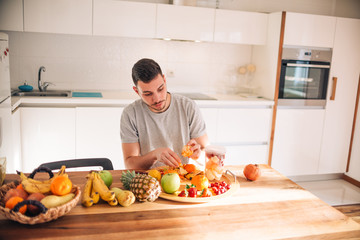 Young caucasian man preparing his healthy smoothie in the morning.