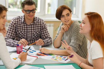 Group of determined learners discussing interesting topic during lesson on courses. Students sitting together at table, looking at each other and talking. Concept of communication and development.