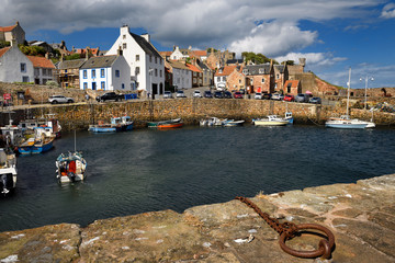 Fisherman on boat returning to Crail Harbour with stone piers and iron mooring ring on the North Sea Scotland UK