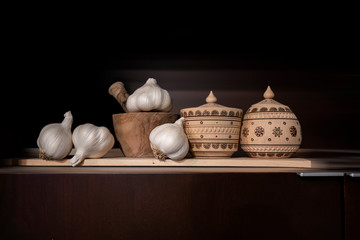 Still life with wooden jars for spices with folk ornament and mortar and garlic