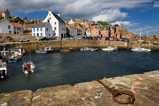 Fisherman on boat returning to Crail Harbour with stone piers and iron mooring ring on the North Sea Scotland UK