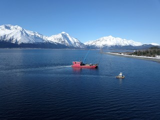 Work boats working together on Alaskan water to bring landing craft and barge into harbor